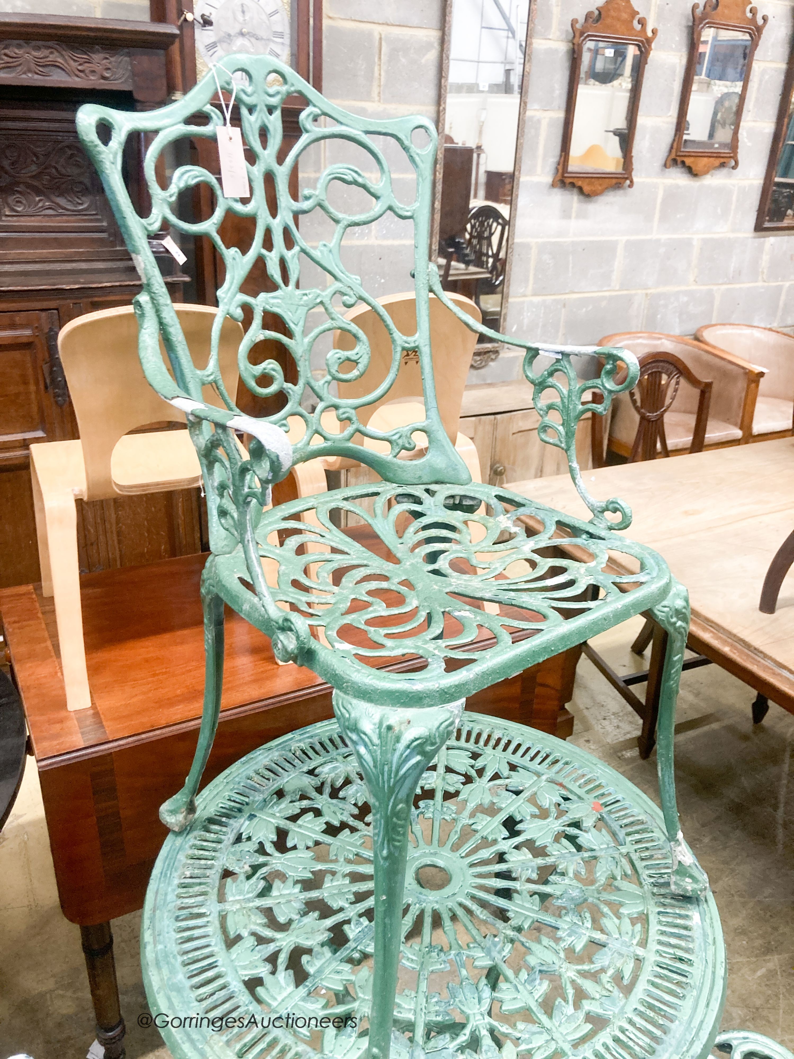 A cast painted aluminium circular garden table, diameter 69cm together with three similar elbow chairs